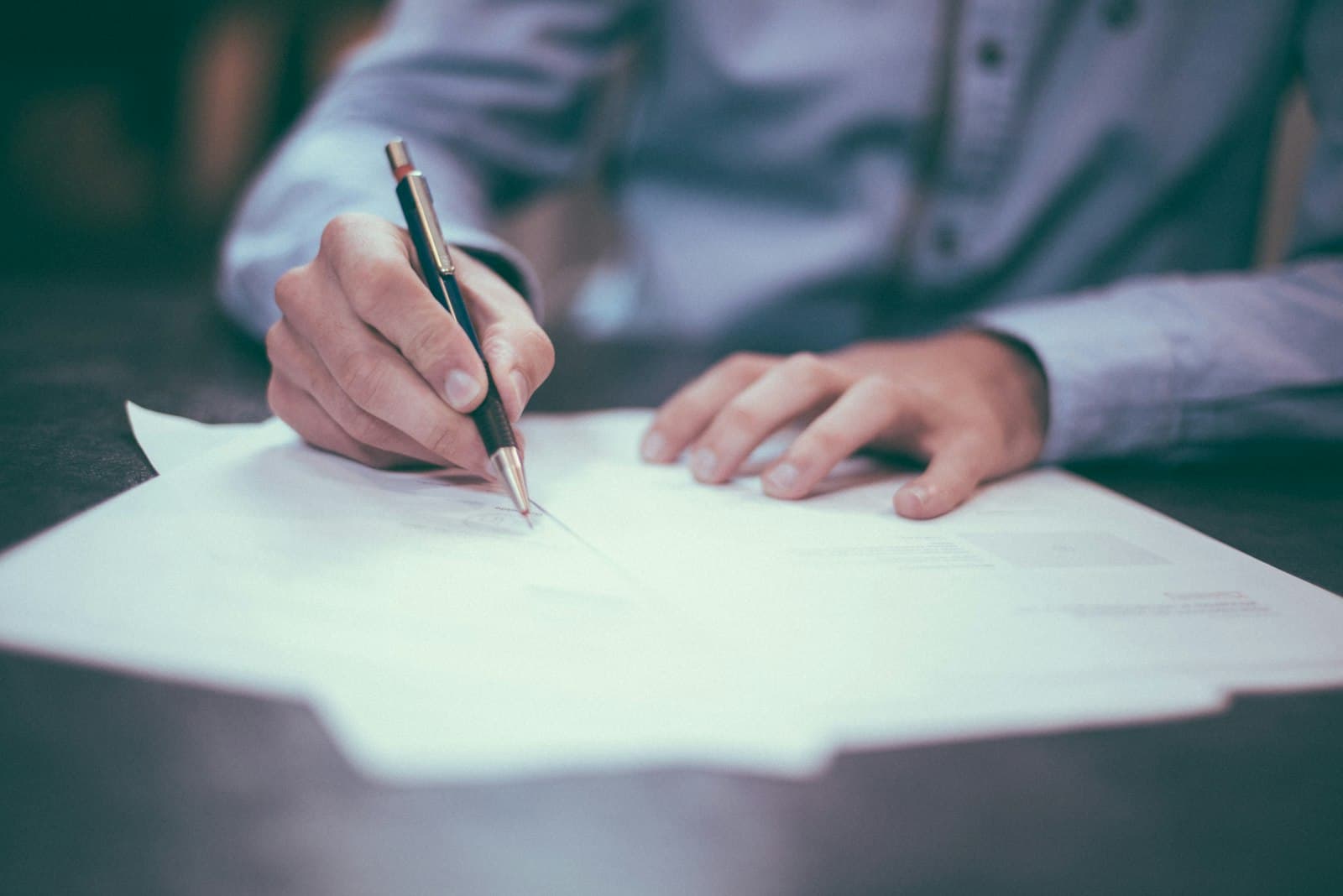 Pessoa a assinar um contrato sobre uma mesa