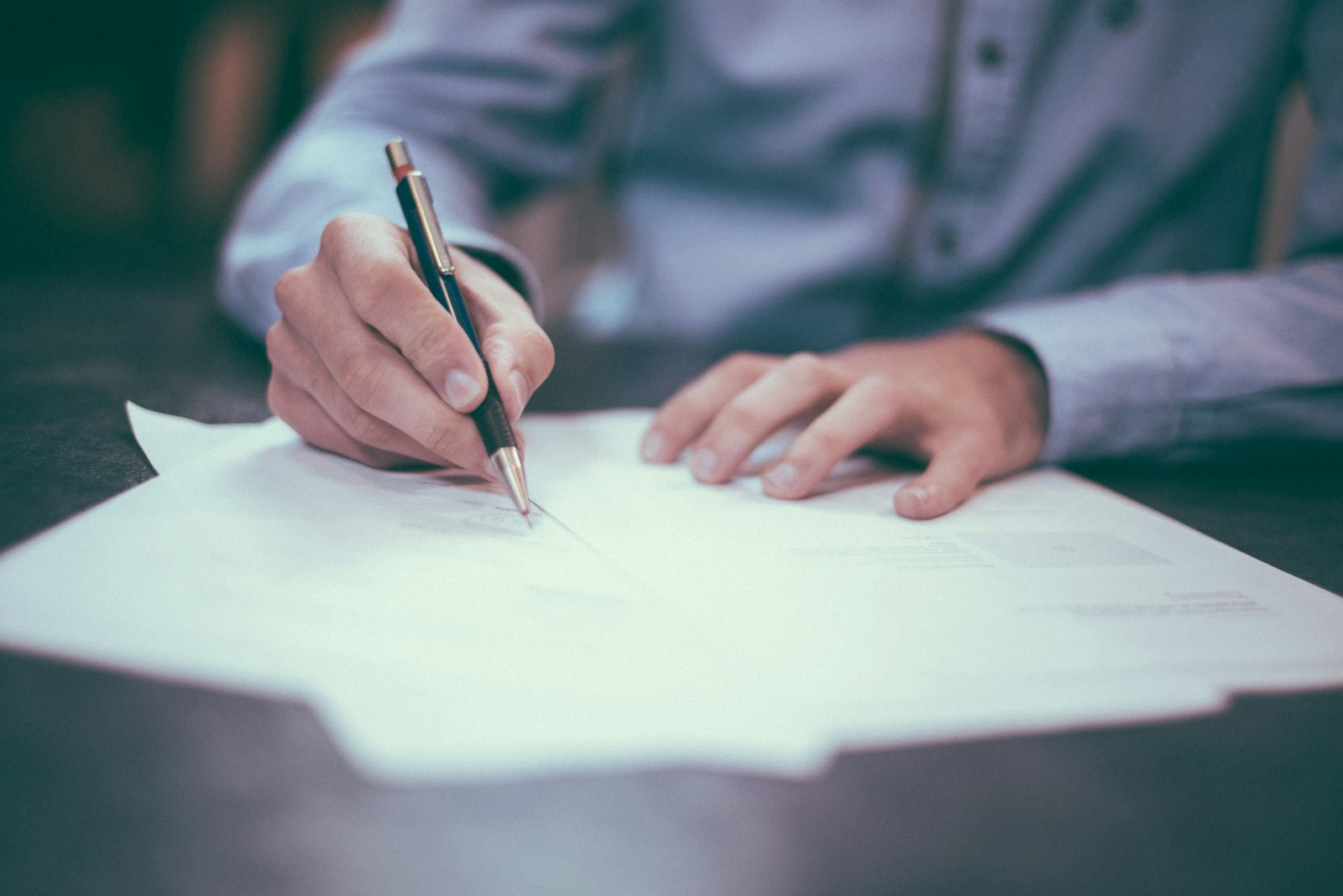 Pessoa a assinar um contrato sobre uma mesa
