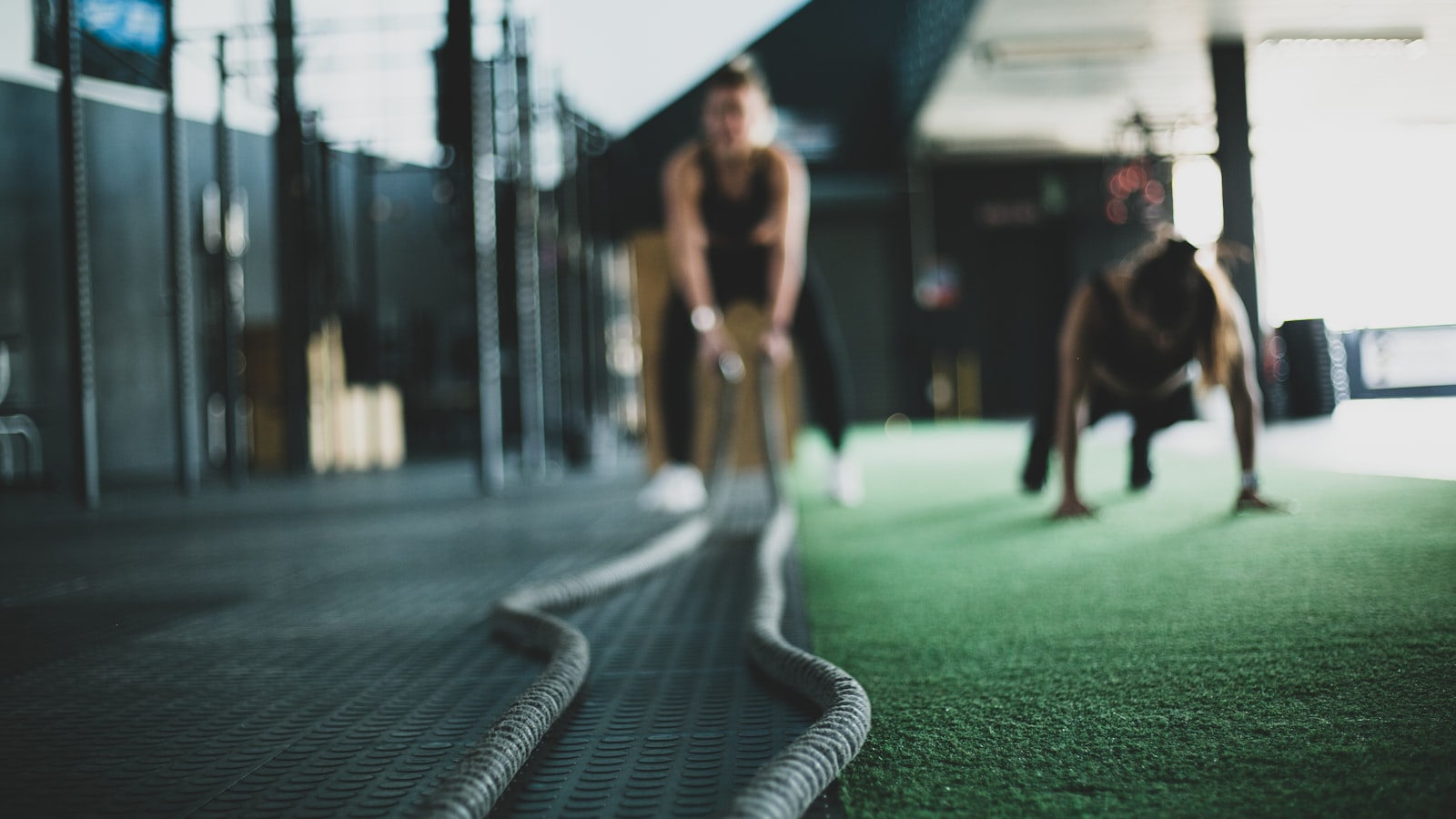Duas pessoas a treinar num ginásio, com cordas de treino em primeiro plano