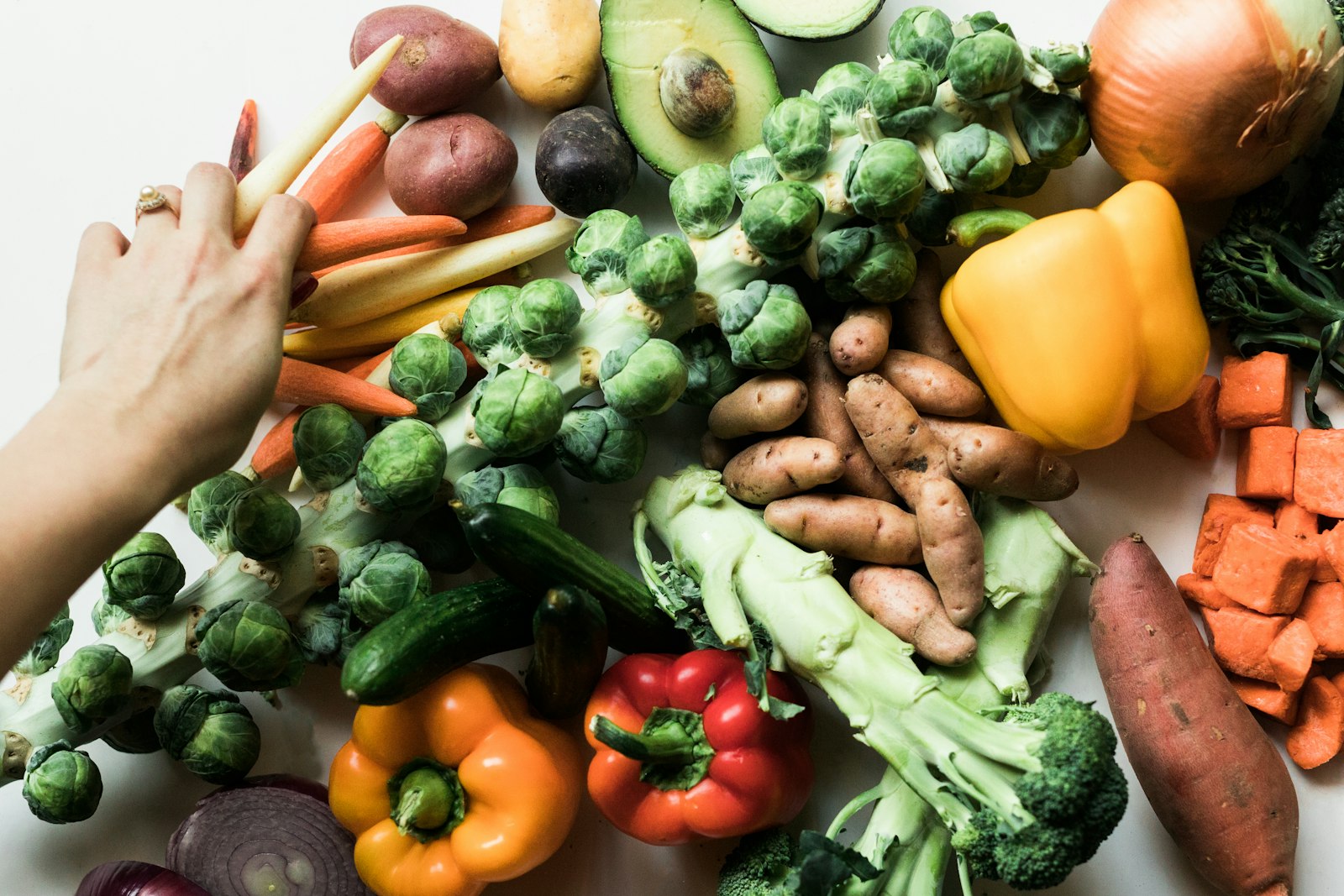 Variedade de legumes frescos dispostos sobre uma superfície branca