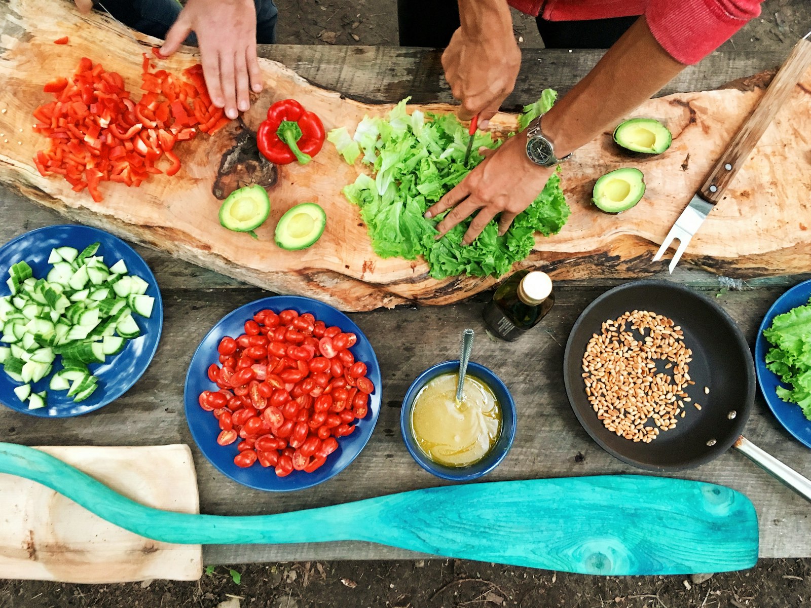 Duas pessoas a preparar legumes frescos numa bancada de madeira