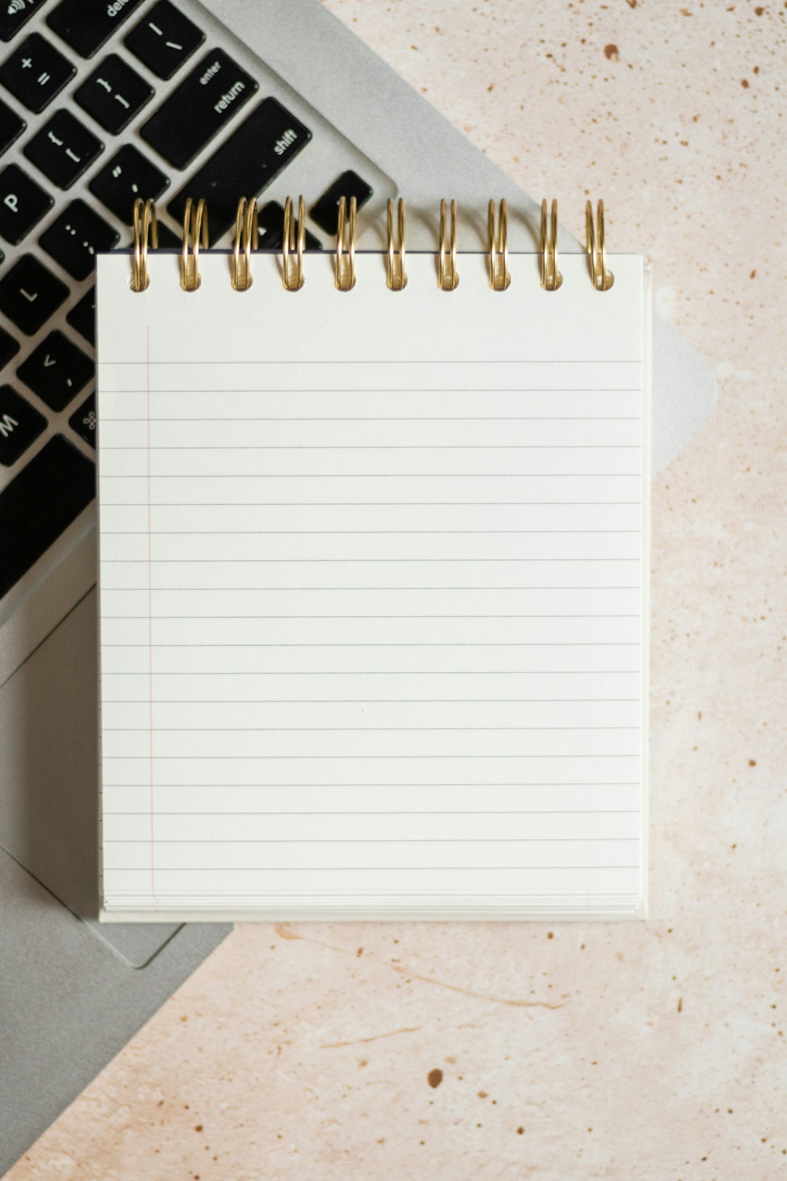 Caderno de notas em espiral pousado sobre um computador portátil