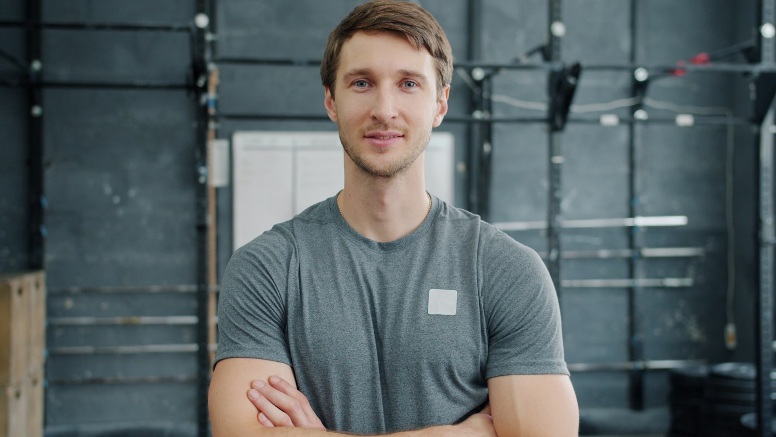 Personal trainer de braços cruzados numa sala de musculação